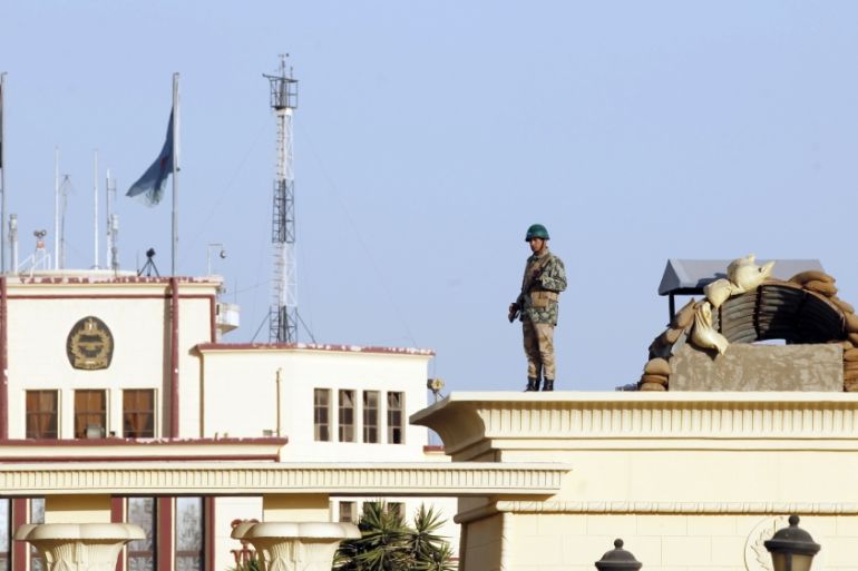 Soldier stands guard on top of a column outside Almaza military airbase, where a military funeral ceremony of security personnel killed in attacks in Sinai is being held, in Cairo
