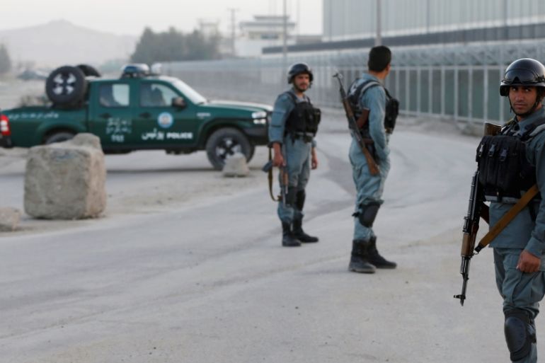 Afghan policemen keep watch near the site of a bomb blast in Kabul,