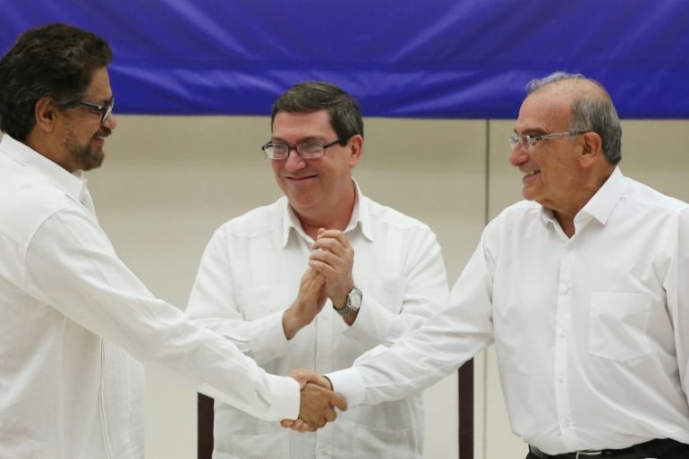 Colombia''s FARC lead negotiator Ivan Marquez and Colombia''s lead government negotiator Humberto de la Calle shake hands while Cuba''s Foreign Minister Bruno Rodriguez looks on, after signing a final p