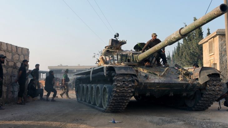 Rebel fighters ride a tank in an artillery academy of Aleppo