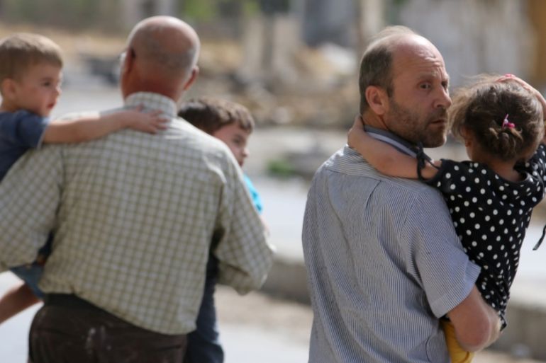 Men carry children away from a damaged site after airstrikes on the rebel held al-Qaterji neighbourhood of Aleppo