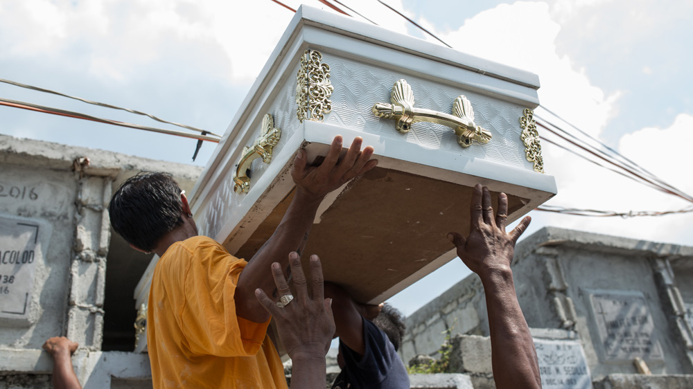 Cemetery workers put the casket of Vicente Batiancila into its temporary burial location. The family received a high interest loan from a loan shark to finance the cost of burial   [Paul Ratje/Al Jazeera] 