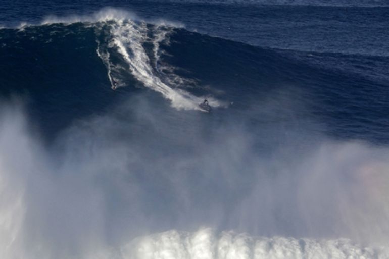 A surfer rides a huge wave at Praia do Norte at Nazare, Portugal