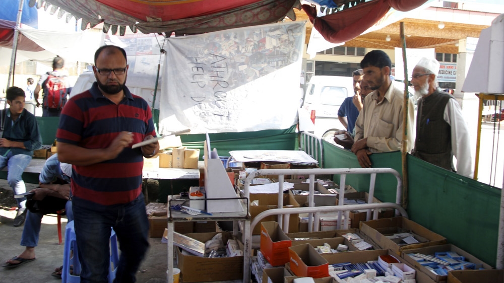 Sajad Ahmad Zaz gives medicine to patients at the Athrout camp in the SMHS compound  [Zahid Rafiq/Al Jazeera]