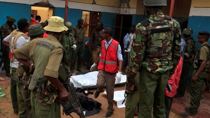 Police officers stand by dead bodies after an attack by Islamist militants from the Somali group al Shabaab in Mandera