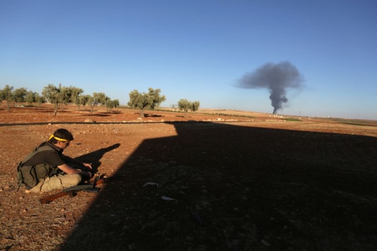 A rebel fighter sits near rising smoke from al-Bab city, northern Aleppo province