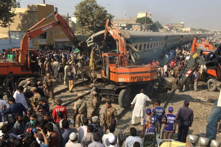Rescuers workers use heavy machinery on the car of a train which crashed outside Karachi,