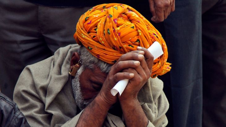 A man sits in a queue to deposit his old high denomination banknotes in Ajmer