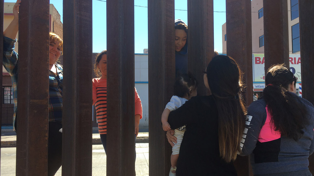 Families reunite through the border fence on the US border [Teresa Bo/Al Jazeera]