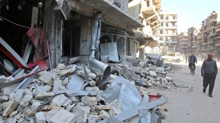 Men walk past damaged shops at a site hit yesterday by air strikes in the rebel held al-Shaar neighbourhood of Aleppo