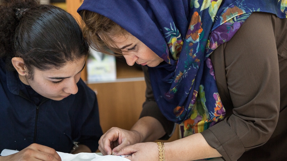 Two war victims attend a tailoring lesson to help them learn to work autonomously [Arianna Pagani/Al Jazeera]