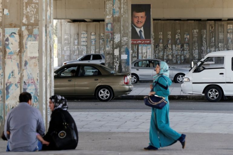 A woman walks past a poster of Jordan''s King Abdullah near the General Intelligence directorate offices near al Baqaa Refugee Camp