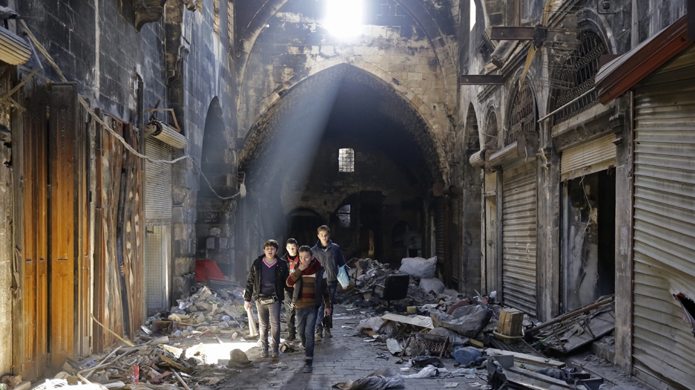 Syrian children walk down a damaged street in the old city of Aleppo [Louai Beshara/AFP]