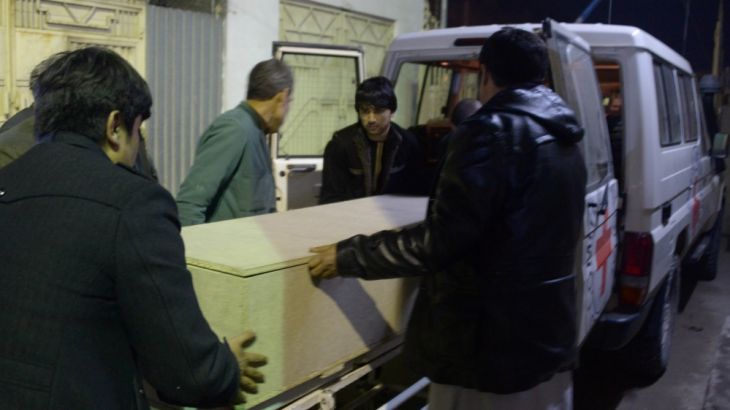 Afghan men unload a coffin of killed ICRC employee from a car at a hospital in Mazar-i-Sharif