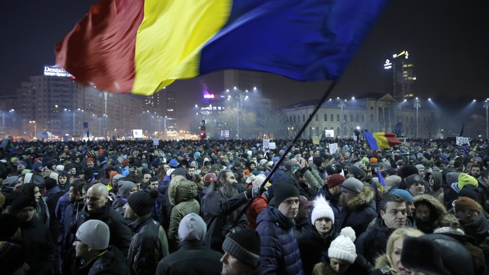 Romanians with anti-government slogans during a protest rally in front of government headquarters [EPA]