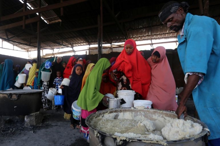 A volunteer serves internally displaced Somali people with cooked food from the WFP feeding program at the Sorrdo camp in Hodan district of Somalia''s capital Mogadishu