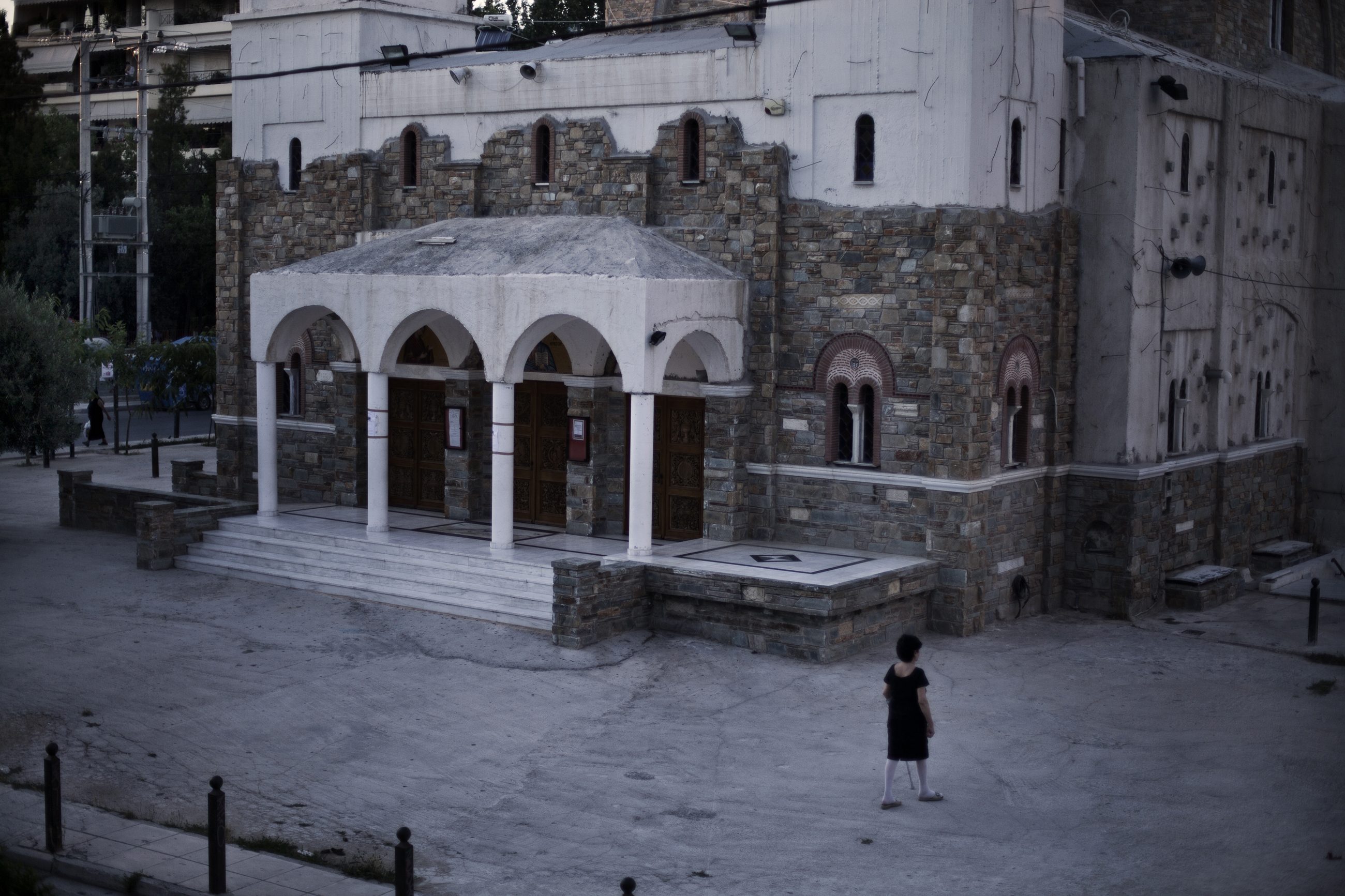 A woman walks by Aghios Dimitris Church just in front of Emmy's house [Paulo Siqueira/Al Jazeera]
