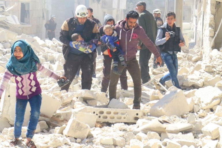 People and a civil defence personnel carry children at a damaged site after an air strike on rebel-held Idlib city