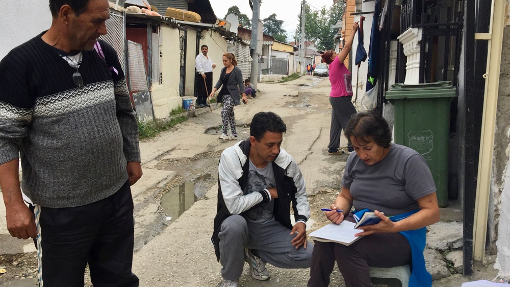 
Ljatifa Sikovska, who runs an NGO called Ambrela, fills out health insurance forms for an illiterate family in Shutka [Valerie Hopkins/Al Jazeera]
