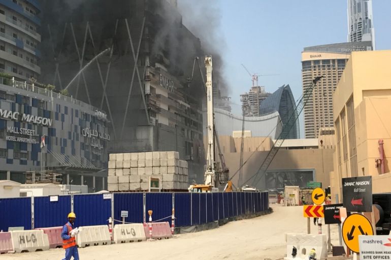 Worker walks as smoke rises following a fire at a tower under construction in Dubai''s Downtown district