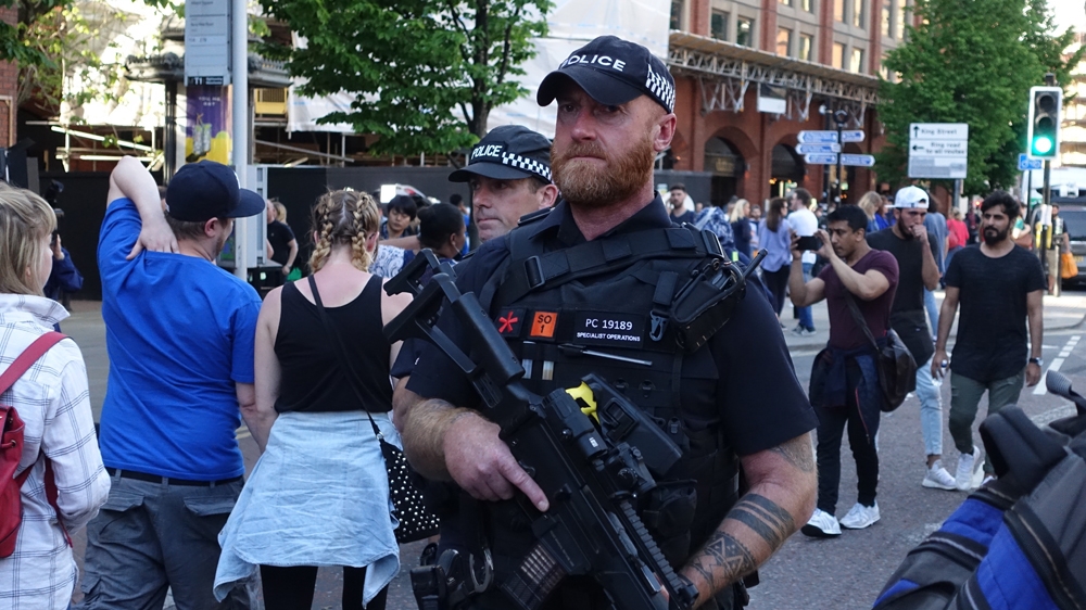 Armed officers patrol the vigil in Manchester city centre [Shafik Mandhai/Al Jazeera]