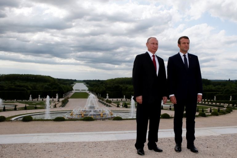 French President Emmanuel Macron and Russian President Vladimir Putin pose in the gardens of the Versailles Palace following their meeting in Versailles