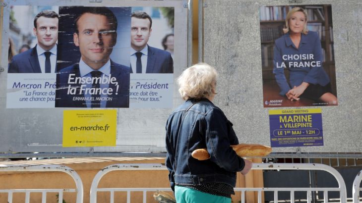 A woman walks past new official posters for the candidates in the 2017 French presidential election in Nice