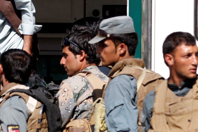 Afghan policemen transport a dead body of a police officer after gunmen attack in Jalalabad city