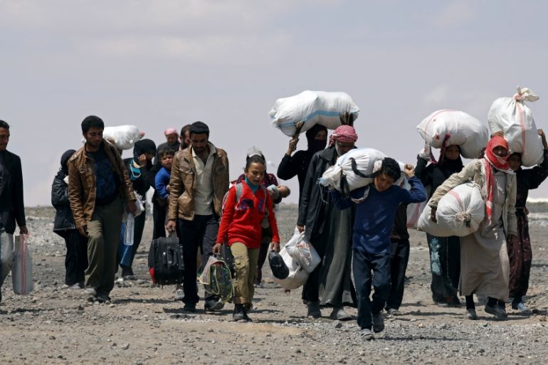 Internally displaced people who fled Raqqa city carry their belongings as they leave a camp in Ain Issa