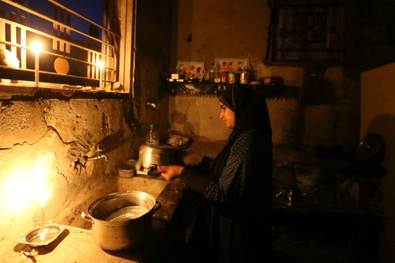 Palestinian girl cleans the kitchen of her house during power cut in the southern Gaza Strip