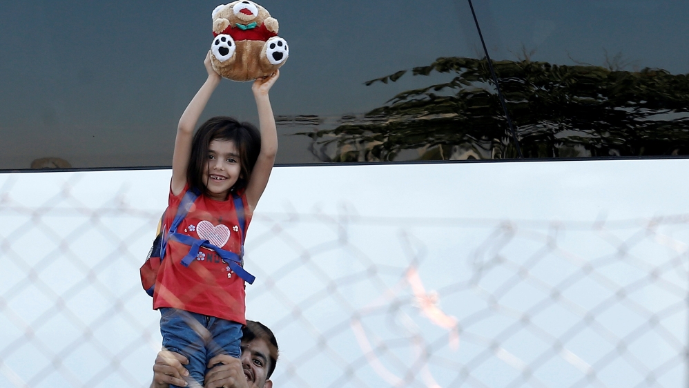 A girl holds up a teddy bear during a police operation to clear out Elliniko [Costas Baltas/Reuters]