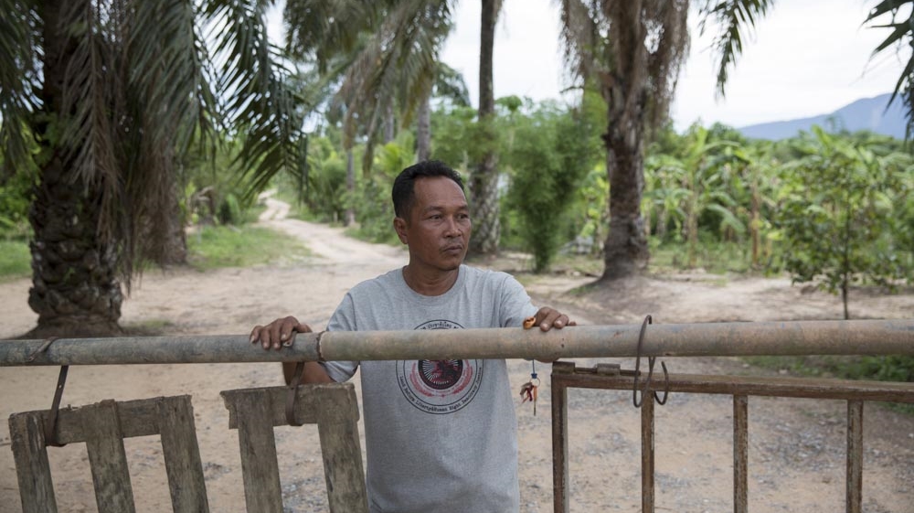 Tawat Ruangsi, 48, stands at the main entrance and security post to Klong Sai Pattana village after having just closed the gate at 6pm. The village tries to limit the number of vehicles entering and leaving during the night and reopens at 6am. In total, the village has four security posts which are manned 24 hours a day by the villagers who take turns in small groups of three to four people [Luke Duggleby/Al Jazeera]