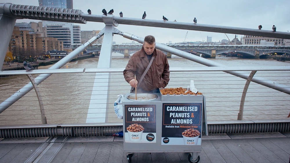 Beta's father Paulin at work selling peanuts on Millennium Bridge, London [Screengrab/Al Jazeera]