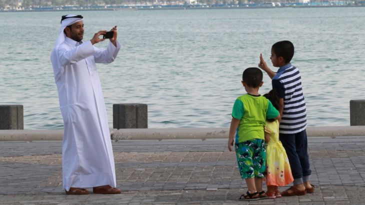 Man takes a picture of his children on the corniche in Doha