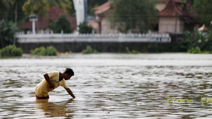 A man searches the water on a flooded road in Dodangoda village in Kalutara