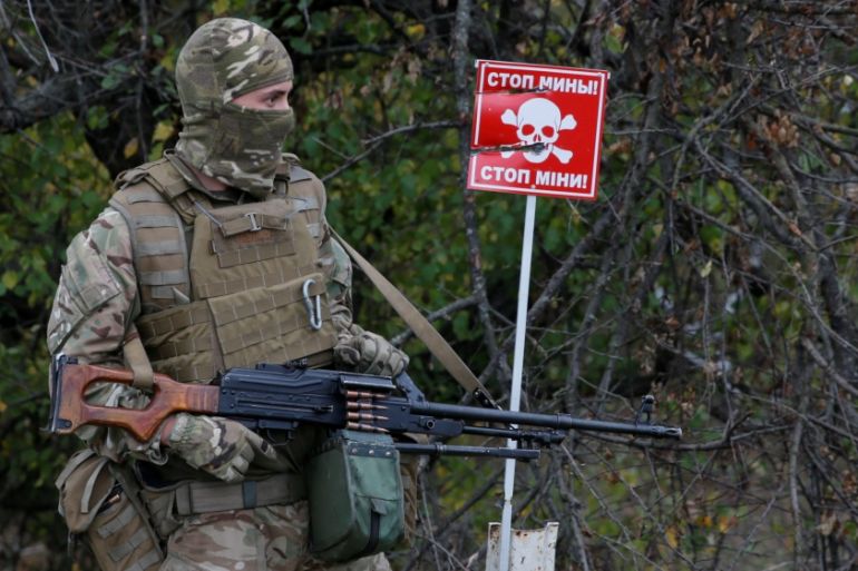 A member of Ukrainian armed forces stands guard next to a mine sign at a check point located on the contact line between pro-Moscow rebels and Ukrainian troops, in the settlement of Stanytsia Luhanska