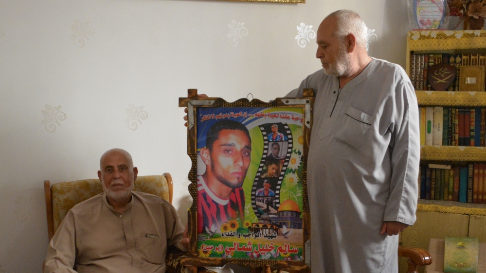 Khalil Shamaly holds a photo of his son, Salem, who was shot dead by an Israeli sniper during a ceasefire [Mersiha Gadzo/Al Jazeera]