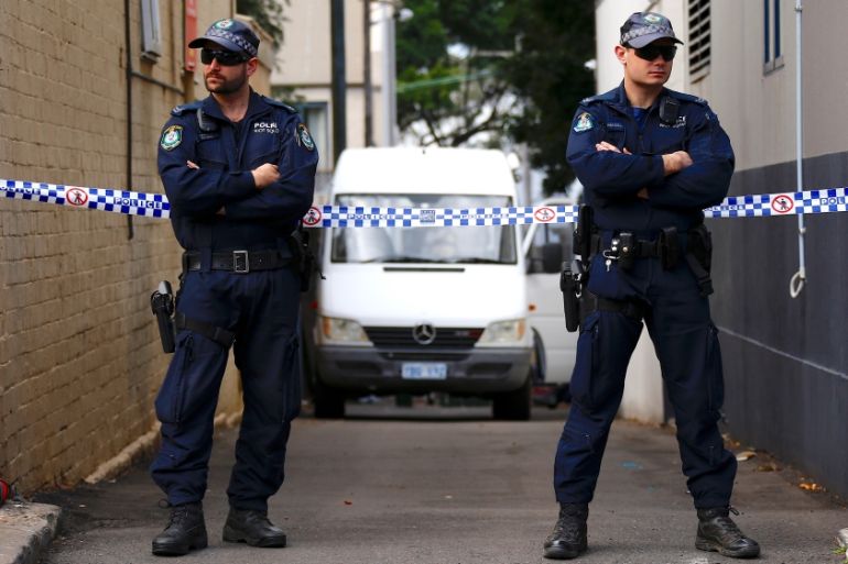 Police officers block a small alley where police vans are parked at a home being searched after Australian counter-terrorism police arrested four people in raids late on Saturday across several Sydne