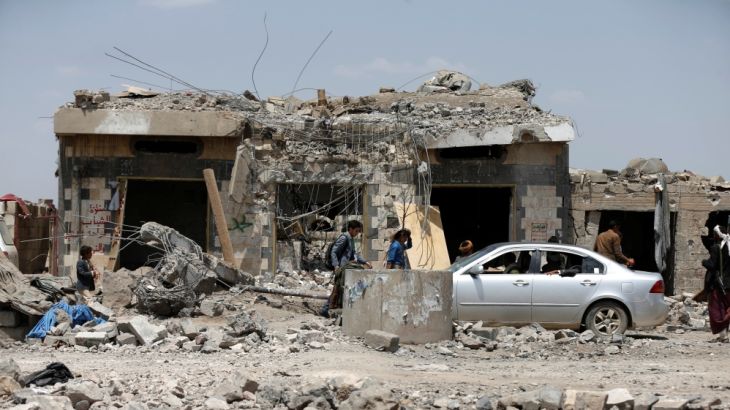 People walk at the site of Saudi-led air strikes in Arhab area, north of Sanaa