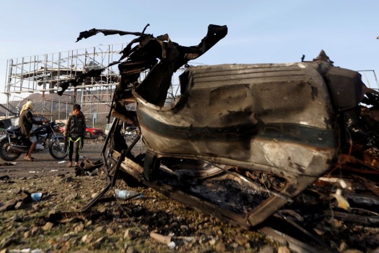Boy looks at the wreckage of a taxi car destroyed by a Saudi-led air strike on a checkpoint of the armed Houthi movement near Sanaa
