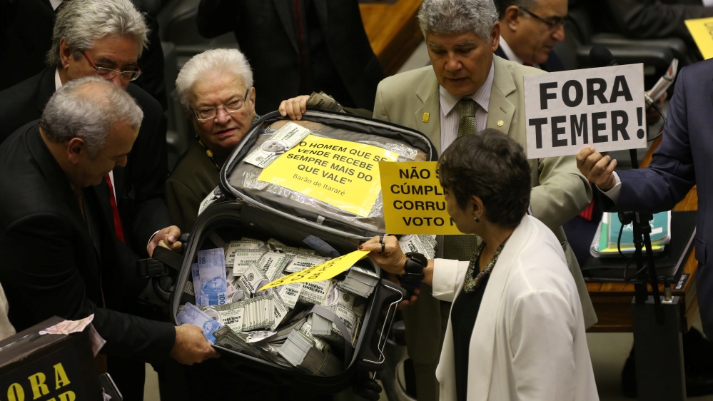 Opposition deputies hold a suitcase with fake money before the vote in congress [Adriano Machado/Reuters]