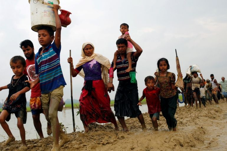 Rohingya refugees walk on the muddy path after crossing the Bangladesh-Myanmar border in Teknaf