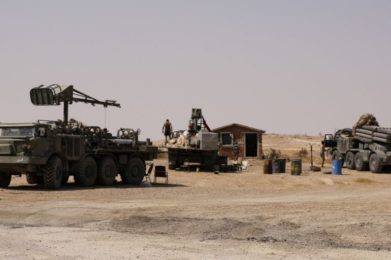 A man stands near military vehicles that belong to the Syrian army in Deir al-Zor