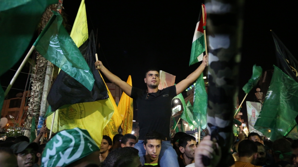 Palestinians wave Fatah and Hamas flags after the 2014 Israeli war on Gaza [AFP] 