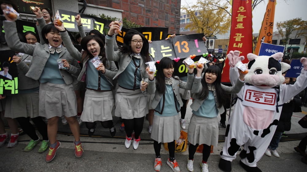 Students cheer for their seniors in front of a college entrance examination hall [Kim Hong-Ji/Reuters]