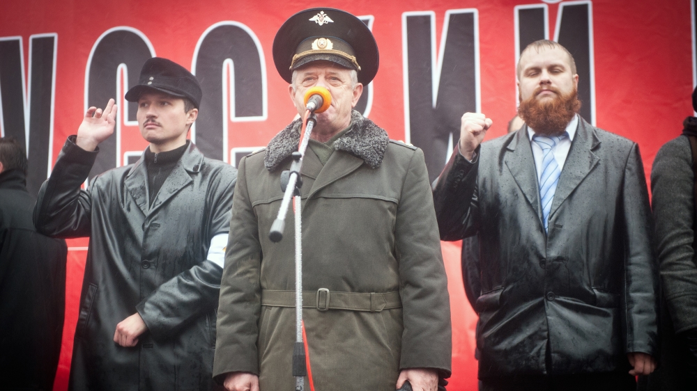 Retired Russian colonel Vladimir Kvachkov speaks at the 2011 Russian march, flagged by Georgy Borovikov (left) and Dmitry Dyomushkin (right) [Sergey Kozmin/Al Jazeera]