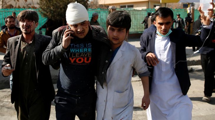 People assist an injured man after a blast in Kabul