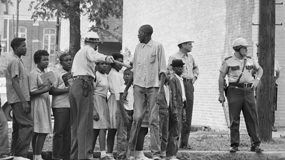 Children participating in a Civil Rights protests wait for a police van to take them to jail in Birmingham, Alabama in May 1963 [Bettman/Getty Images]