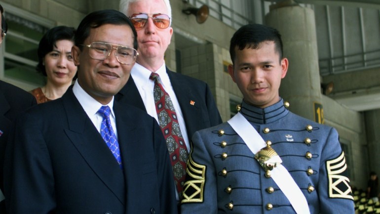 Hun Sen, in a suit, stands next to Hun Manet, in a military uniform.