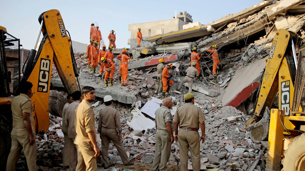 At least 100 rescue workers with cranes and chainsaws sift through the debris [Altaf Qadri/AP] 